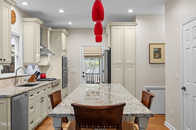 kitchen with a sink, stainless steel appliances, light wood-type flooring, light stone counters, and backsplash