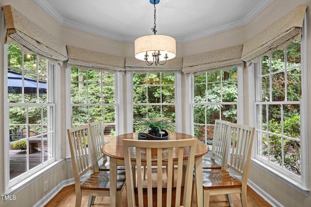 sunroom / solarium featuring wood finished floors, healthy amount of natural light, baseboards, ornamental molding, and a chandelier