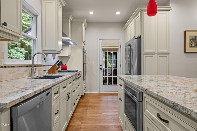kitchen with appliances with stainless steel finishes, a sink, light wood-style flooring, extractor fan, and recessed lighting