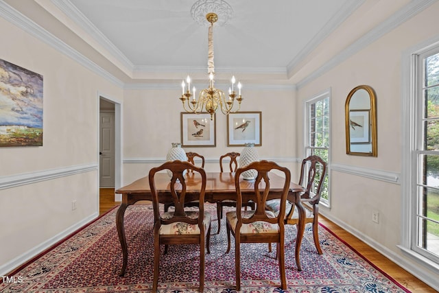 dining space featuring healthy amount of natural light, a chandelier, wood finished floors, ornamental molding, and baseboards