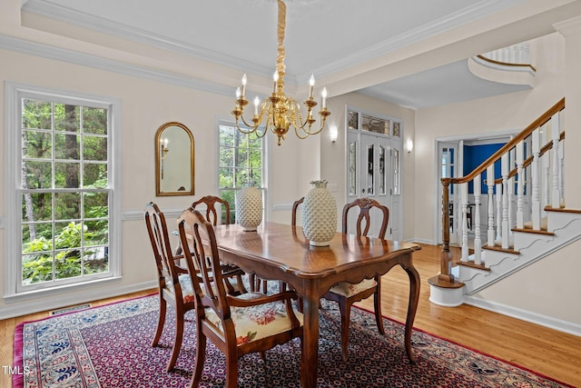 dining room with light wood-type flooring, a chandelier, healthy amount of natural light, stairway, and crown molding