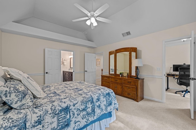 bedroom featuring an office area, light colored carpet, vaulted ceiling, ceiling fan, and ensuite bath