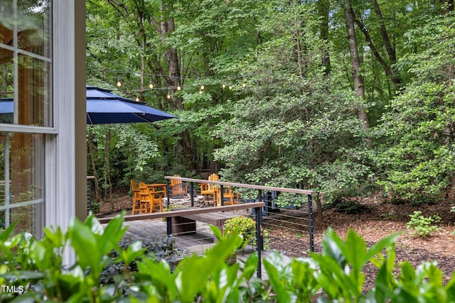 view of yard with a wooden deck and a wooded view