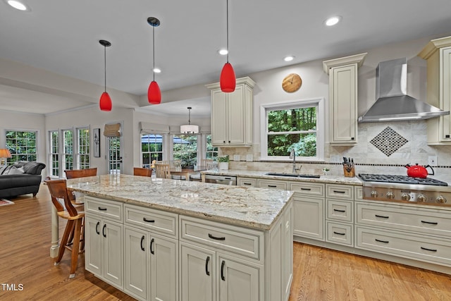 kitchen featuring wall chimney exhaust hood, a sink, appliances with stainless steel finishes, tasteful backsplash, and recessed lighting