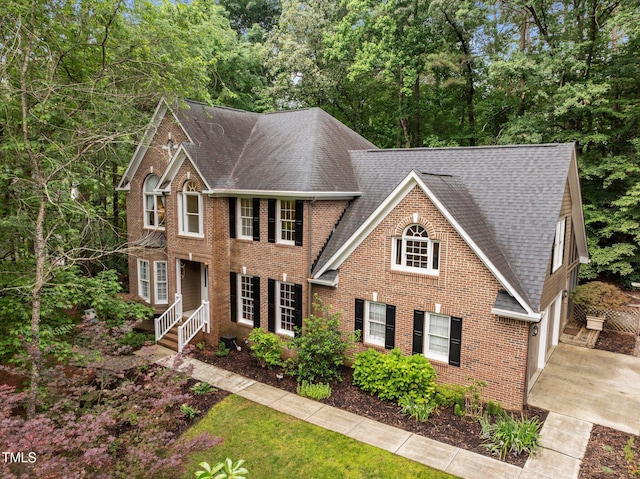 view of front of home with roof with shingles, brick siding, concrete driveway, and a garage