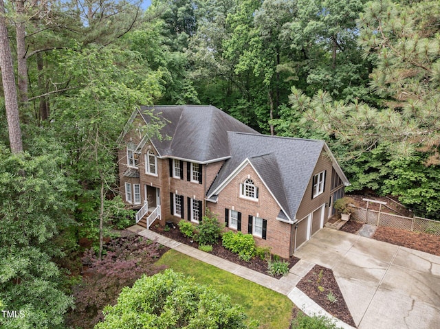 view of front of property featuring concrete driveway, an attached garage, a shingled roof, and brick siding