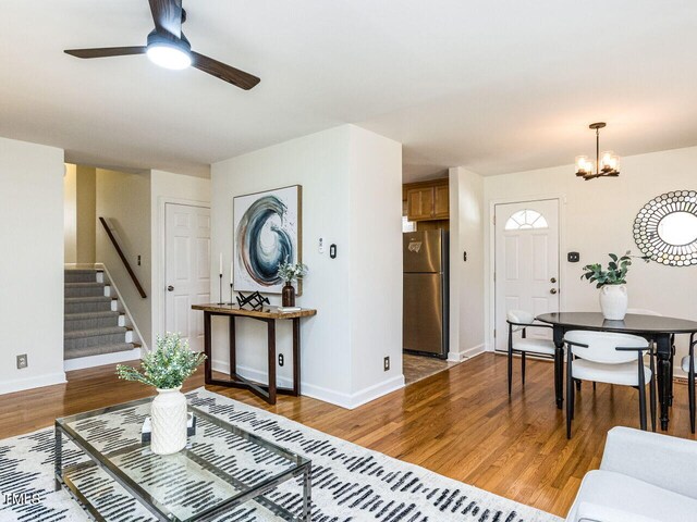3818 Hillgrand Dr, Durham, NC 27705 - living room with baseboards, light wood finished floors, stairs, and ceiling fan with notable chandelier