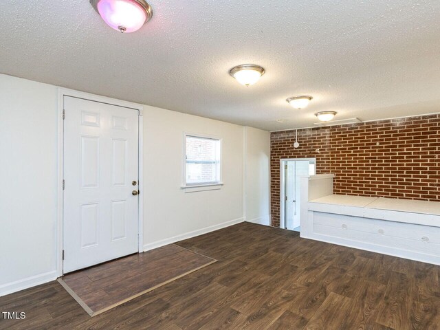 3818 Hillgrand Dr, Durham, NC 27705 - unfurnished living room with brick wall, baseboards, wood finished floors, and a textured ceiling