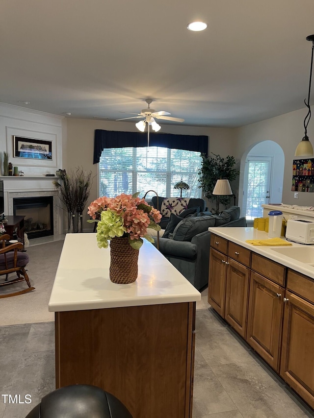 kitchen featuring brown cabinetry, arched walkways, a ceiling fan, and open floor plan