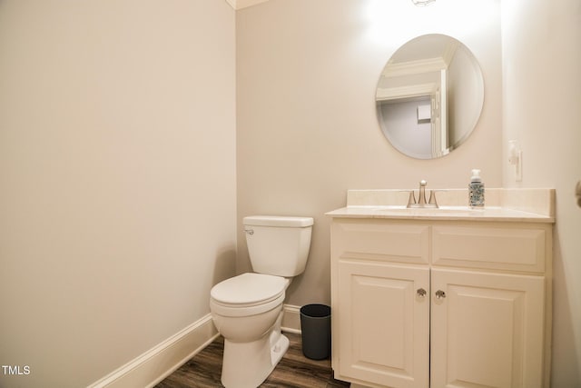 bathroom with wood finished floors, baseboards, vanity, toilet, and ornamental molding