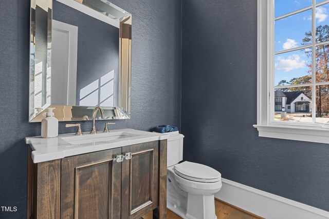 bathroom featuring wood finished floors, toilet, vanity, and plenty of natural light