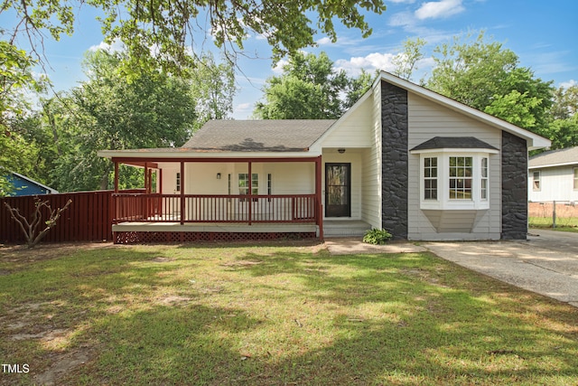 108 Carmichael Ln, Spring Lake, NC 28390 - view of front facade featuring stone siding, a shingled roof, covered porch, fence, and a front lawn