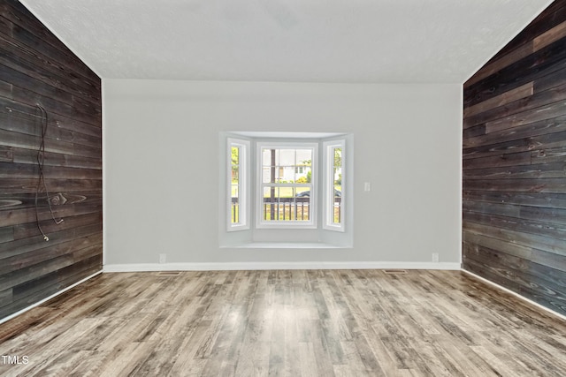 108 Carmichael Ln, Spring Lake, NC 28390 - spare room featuring baseboards, wood walls, wood finished floors, and lofted ceiling