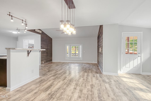 108 Carmichael Ln, Spring Lake, NC 28390 - unfurnished living room featuring wood walls, a chandelier, baseboards, light wood-type flooring, and vaulted ceiling