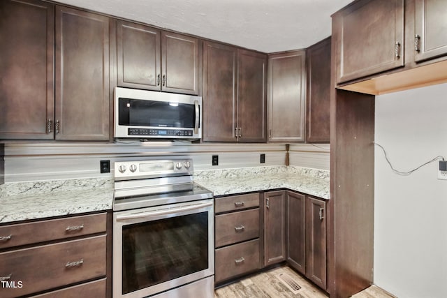 108 Carmichael Ln, Spring Lake, NC 28390 - kitchen with light stone counters, light wood-style floors, stainless steel appliances, and dark brown cabinetry