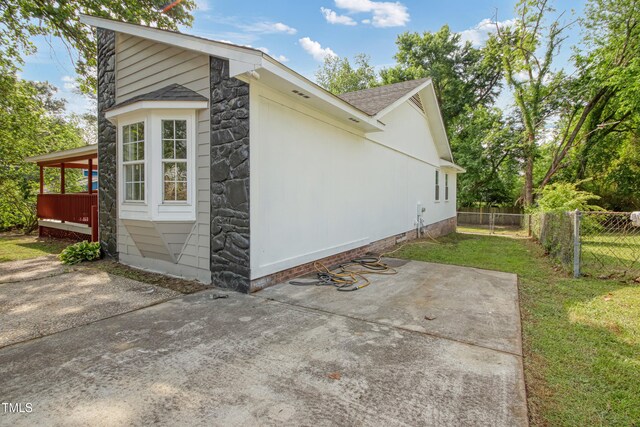 108 Carmichael Ln, Spring Lake, NC 28390 - view of side of property featuring a patio, stone siding, a shingled roof, fence, and a yard