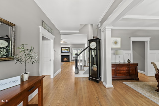 925 Hidden Jewel Ln, Wake Forest, NC 27587 - entryway with light wood finished floors, a lit fireplace, crown molding, stairs, and decorative columns
