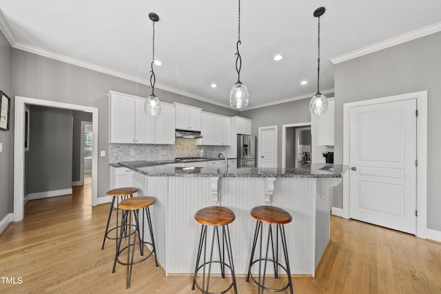 925 Hidden Jewel Ln, Wake Forest, NC 27587 - kitchen with stainless steel appliances, under cabinet range hood, crown molding, white cabinetry, and a breakfast bar