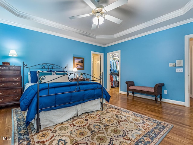 5401 Fire Pink Way, Raleigh, NC 27613 - bedroom featuring wood finished floors, a tray ceiling, a spacious closet, baseboards, and ornamental molding