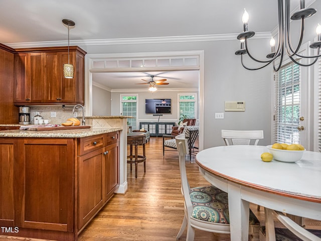 5401 Fire Pink Way, Raleigh, NC 27613 - kitchen with brown cabinetry, ceiling fan, tasteful backsplash, light wood-style floors, and ornamental molding