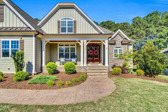 128 Paraggi Ct, Clayton, NC 27527 - craftsman house featuring a front lawn, stone siding, board and batten siding, a porch, and french doors