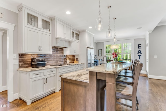 128 Paraggi Ct, Clayton, NC 27527 - kitchen with light wood-style floors, appliances with stainless steel finishes, tasteful backsplash, and a breakfast bar area