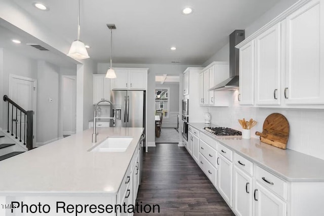 kitchen with a sink, wall chimney exhaust hood, appliances with stainless steel finishes, visible vents, and recessed lighting
