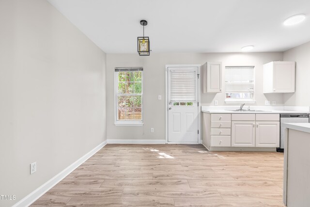 1628 Briarmont Ct, Raleigh, NC 27610 - kitchen with a sink, light countertops, light wood-style flooring, baseboards, and white cabinets