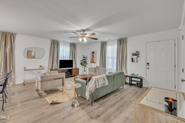 living room featuring baseboards, a ceiling fan, and light wood-style flooring
