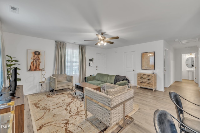 living room with visible vents, a ceiling fan, light wood-style floors, and baseboards