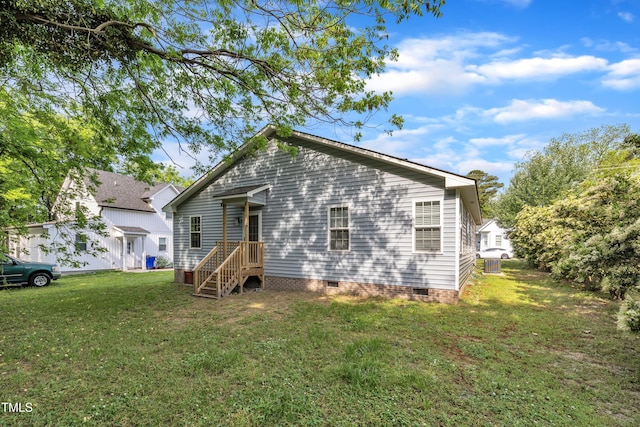 rear view of house with a lawn, cooling unit, and crawl space
