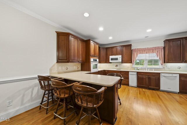 406 N Wakefield St, Zebulon, NC 27597 - kitchen with white appliances, crown molding, light countertops, light wood-style flooring, and a kitchen bar