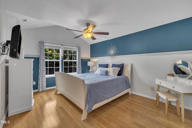 bedroom featuring lofted ceiling, wood finished floors, baseboards, and ceiling fan
