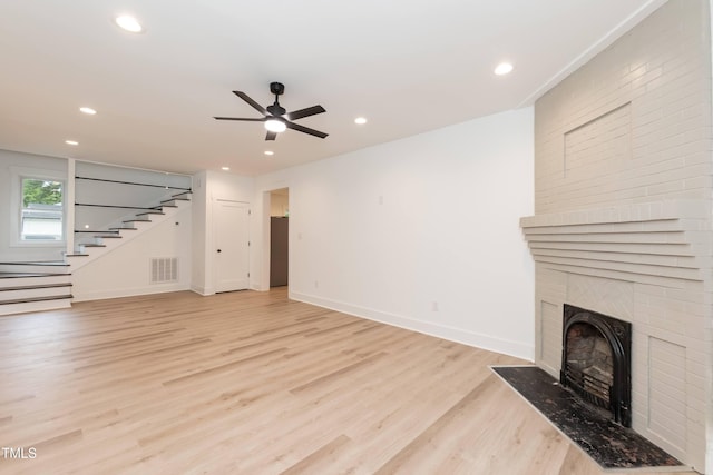 unfurnished living room with a fireplace, a ceiling fan, light wood-style floors, stairway, and recessed lighting