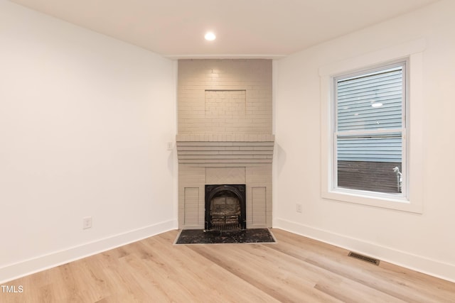 detailed view of wood finished floors, baseboards, a fireplace, and recessed lighting