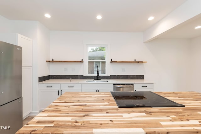 kitchen with butcher block counters, stainless steel appliances, a sink, open shelves, and recessed lighting