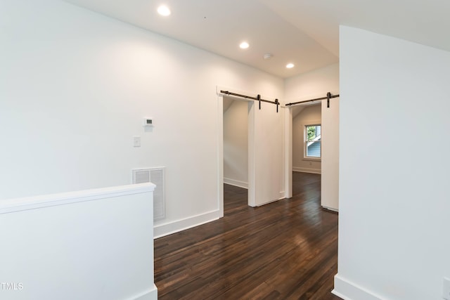 hallway featuring a barn door, dark wood-type flooring, recessed lighting, and baseboards