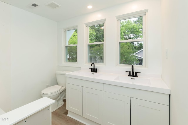 bathroom with toilet, wood finished floors, double vanity, and recessed lighting