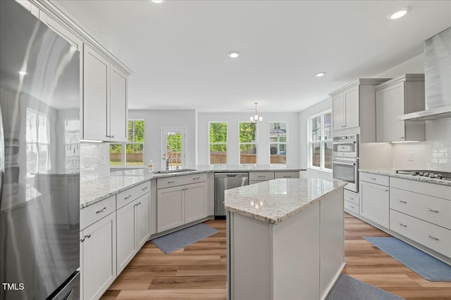 1005 Whispering Creek Ct, Knightdale, NC 27545 - kitchen featuring stainless steel appliances, a peninsula, a sink, backsplash, and wall chimney range hood