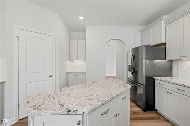 1005 Whispering Creek Ct, Knightdale, NC 27545 - kitchen featuring arched walkways, stainless steel fridge, tasteful backsplash, light wood-style floors, and light stone countertops
