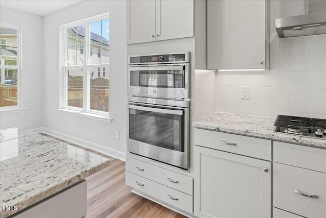 1005 Whispering Creek Ct, Knightdale, NC 27545 - kitchen with stainless steel appliances, light wood-style flooring, tasteful backsplash, range hood, and light stone countertops