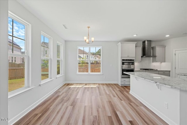 1005 Whispering Creek Ct, Knightdale, NC 27545 - kitchen with stainless steel double oven, wall chimney range hood, a wealth of natural light, and an inviting chandelier