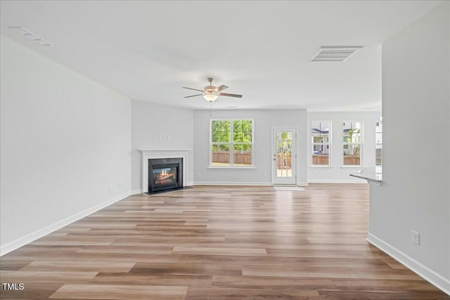 1005 Whispering Creek Ct, Knightdale, NC 27545 - unfurnished living room featuring a fireplace with flush hearth, visible vents, a ceiling fan, light wood-style floors, and baseboards