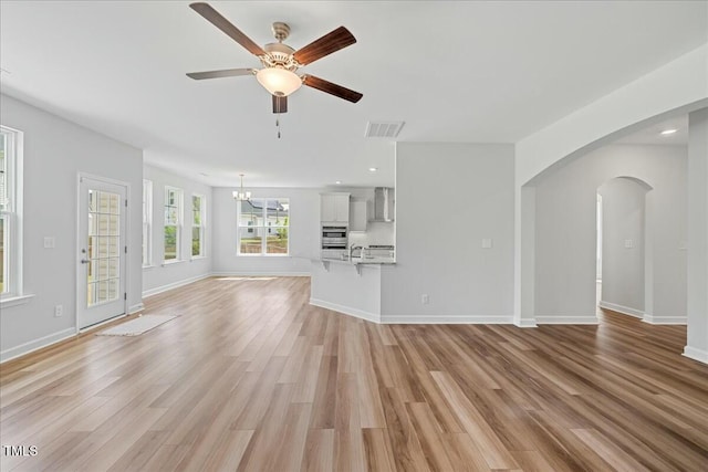 1005 Whispering Creek Ct, Knightdale, NC 27545 - unfurnished living room with visible vents, arched walkways, light wood-style floors, baseboards, and ceiling fan