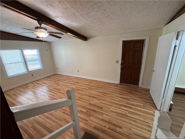 interior space with light wood-type flooring, a ceiling fan, baseboards, and a textured ceiling
