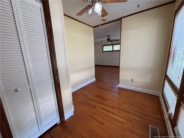 hall with wood finished floors, visible vents, crown molding, and baseboards