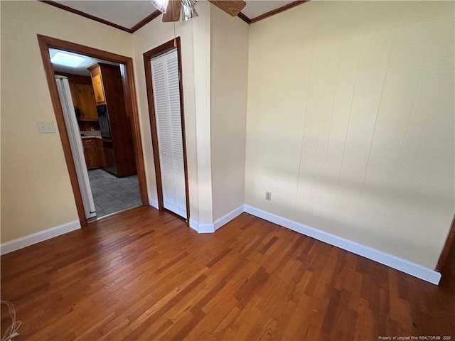 spare room featuring wood finished floors, a ceiling fan, baseboards, and ornamental molding