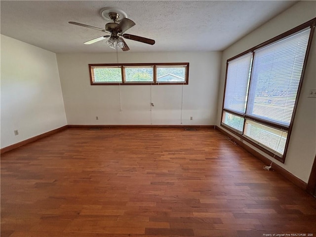 spare room with baseboards, a ceiling fan, wood finished floors, and a textured ceiling