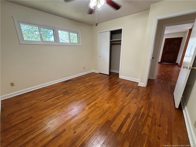 unfurnished bedroom with a ceiling fan, a closet, hardwood / wood-style flooring, baseboards, and visible vents