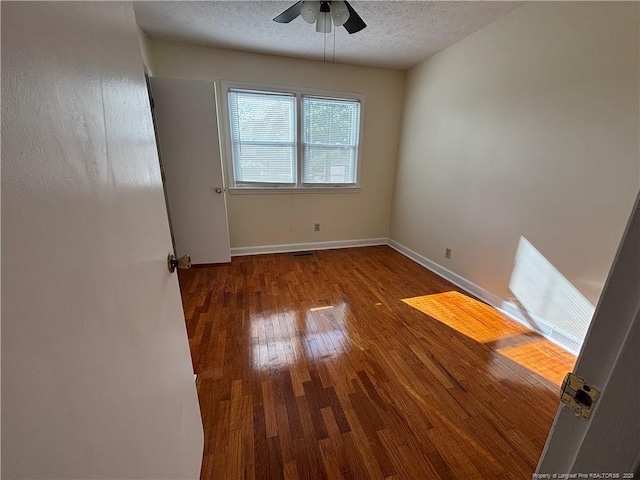 empty room with baseboards, a ceiling fan, wood finished floors, and a textured ceiling